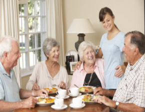 caregiver with seniors eating at dining table